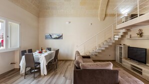 Un salon moderne comprenant un coin repas, un escalier et un téléviseur.