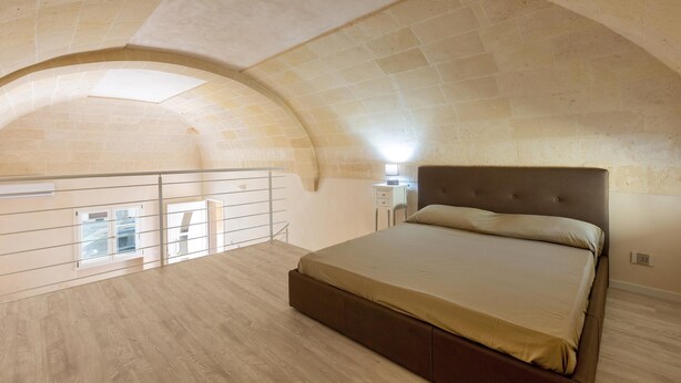 Ein Schlafzimmer mit einem großen Bett, einem Balkon und einer gewölbten Decke.