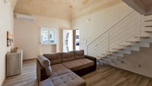 Ein geräumiger Wohnbereich mit moderner Treppe, einem Ecksofa und Holzboden.