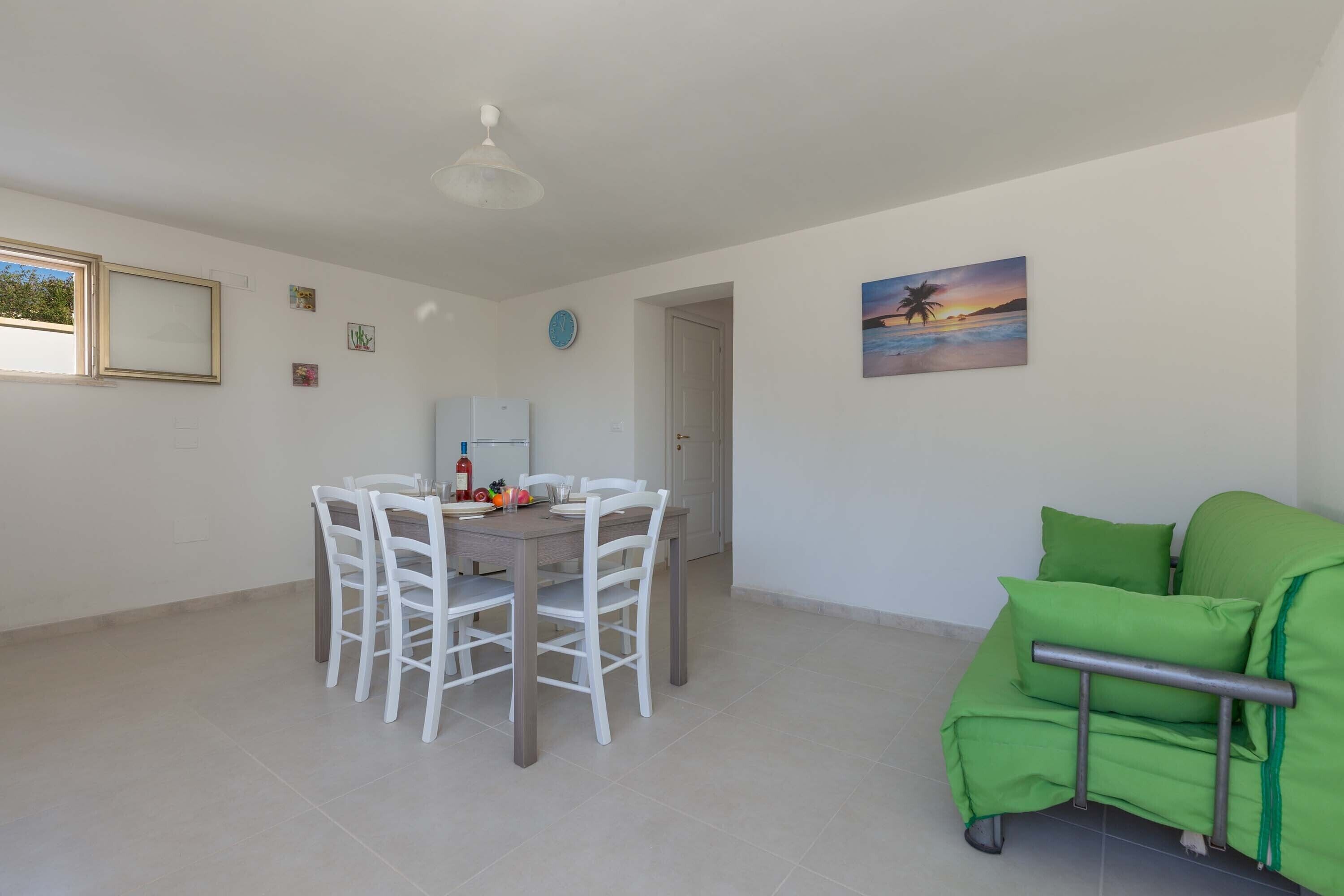 Un coin repas avec une table et des chaises, un canapé vert et un tableau au mur.