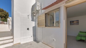 Un apartamento moderno con fachada de baldosas, una ventana con persianas y una silla verde en la sala.