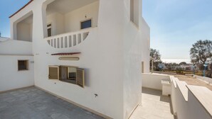 Un edificio de dos pisos con un balcón, una ventana pequeña y una puerta.