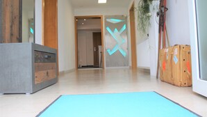 A hallway with a wooden cabinet, a blue mat, and a suitcase.