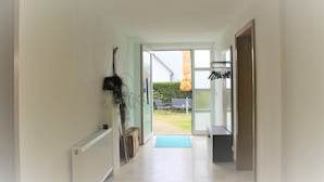 A hallway leading to a glass door entrance with a view of an outdoor patio area.