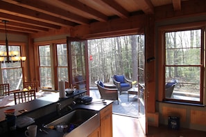 Een houten chalet met keuken, eethoek en terras met buitenmeubels.