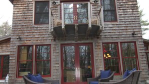 A two-story wooden house with a balcony, large windows, and outdoor furniture. - Stille Wasser, Quiet, secluded spot on Saco River with Dock (Boat lift option) (Buxton)