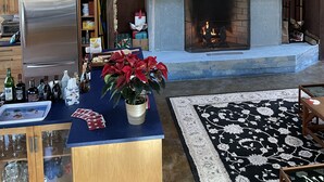 A modern kitchen with a stone fireplace, wooden cabinets, and a blue countertop. - Stille Wasser, Quiet, secluded spot on Saco River with Dock (Boat lift option) (Buxton)