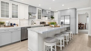 A modern kitchen with white cabinetry, a marble countertop, and stainless steel appliances. - BEACH FACING! Large 3BR - 180 panoramic ocean views, steps to sand and Village! (Carlsbad)