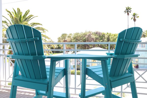 Two turquoise Adirondack chairs with a small table in between, set on a wooden deck with a white railing. - ♥ BEACH CONDO ♥ NEW ♥ SLEEPS 10 ♥ 3 BD 2.5 BA ♥ U1 (Indian Rocks Beach)