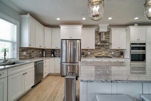 Enjoy cooking in this well-equipped kitchen with a stainless steel refrigerator, dishwasher, and stainless steel range hood.