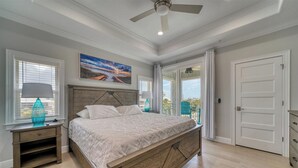 Un dormitorio con una cama de madera, una mesita de noche, una lámpara, un cuadro y vistas a través de una puerta.