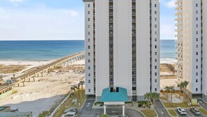 A high-rise hotel with a beach view, multiple balconies, and a parking area. - Best view on the Gulf! Heated pool and beach gear included! Book today!  (Navarre)