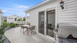 Eine Terrasse mit Tisch, Stühlen, einem Grill und einer Terrassentür.