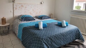 A bedroom with a bed, a round mirror, a small table, and a radiator. - Villa Tanchet-Plage Sea view (Les Sables-d'Olonne)