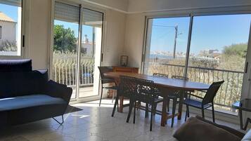 Un salon moderne avec un canapé, une table à manger et des chaises, et une vue sur le paysage urbain à travers de grandes fenêtres.