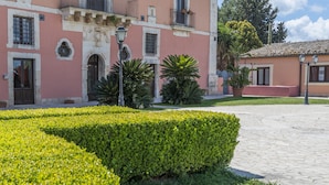 A historic building with a pink facade, multiple windows, and a balcony. - Junior Suite Deluxe - Hotel Lady Lusya ★★★★ (Sicilia)
