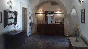 A rustic interior with a stone archway leading to a kitchen area, featuring a wooden counter and a hanging light fixture. - Junior Suite Deluxe - Hotel Lady Lusya ★★★★ (Sicilia)