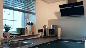 A modern kitchen with a built-in sink, a coffee maker, and a microwave. - Apartment with lake view (Waldeck)