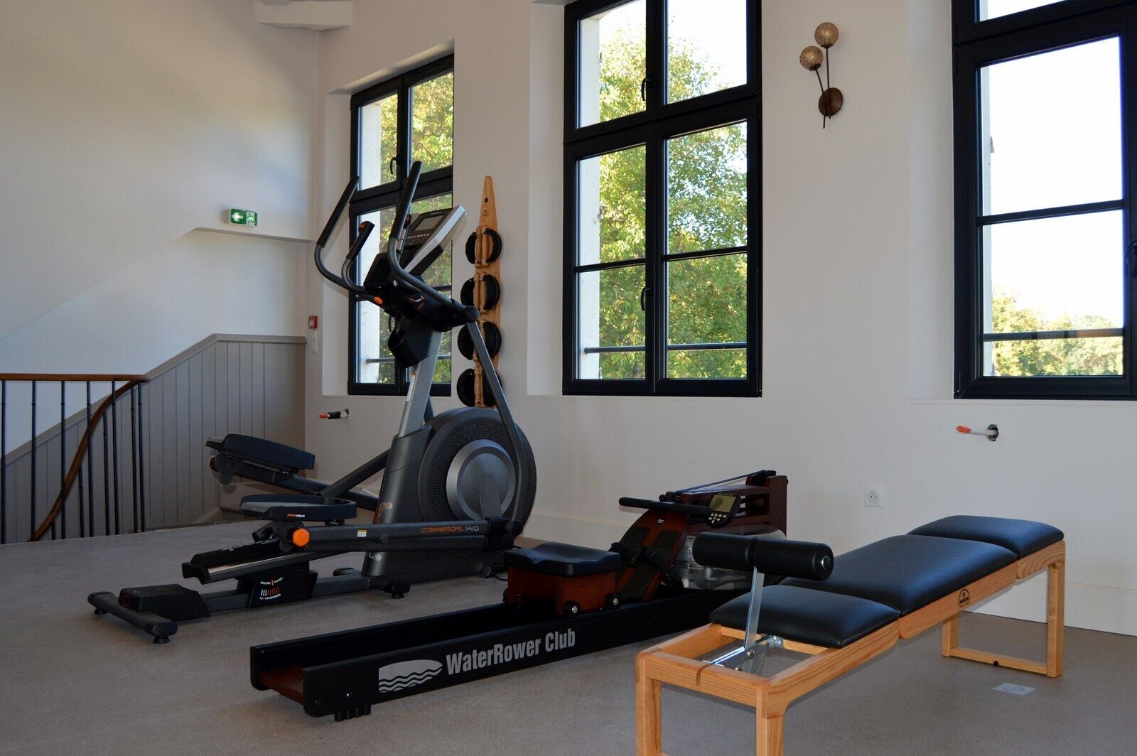 Un gimnasio con una bicicleta estática, una máquina de remo y un banco.