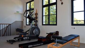 Un gimnasio con una bicicleta estática, una máquina de remo y un banco.