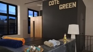 Zona de recepción con mostrador que exhibe toallas y un cartel que dice "COTE GREEN".