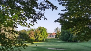 Un campo de golf con un club de campo al fondo.