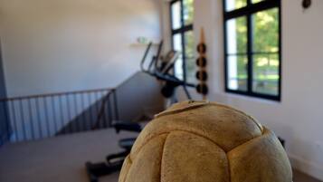 A room with a large, round, textured object in the foreground, a staircase, and a window with a view of greenery.