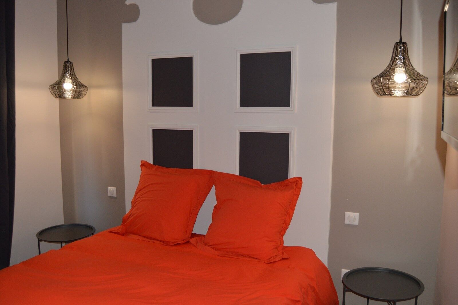 Ein Schlafzimmer mit einem Bett, zwei Kissen, zwei Nachttischen und zwei Hängeleuchten.