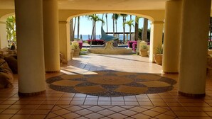 Vestíbulo de hotel con piso de baldosas, columnas y vista al océano.