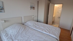 Une chambre à coucher avec un lit, une porte et un mur orné de deux tableaux.
