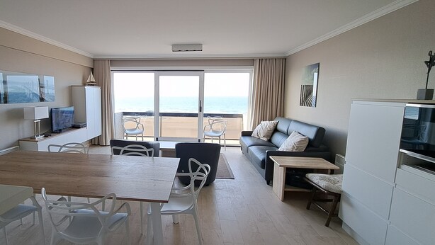 Une chambre d’hôtel avec un coin repas, un canapé, une télévision et vue sur la plage.