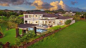 A large, modern house with a swimming pool, multiple rooms, and a well-maintained garden. - Spectacular home with ocean and golf course views! (Koloa)