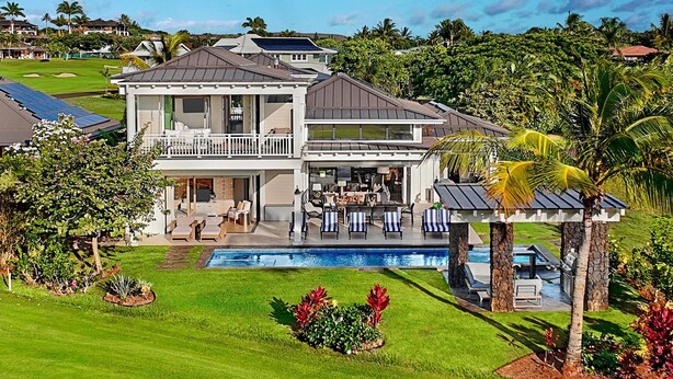 A two-story house with a pool, outdoor seating, and a view of a golf course. - Spectacular home with ocean and golf course views! (Koloa)