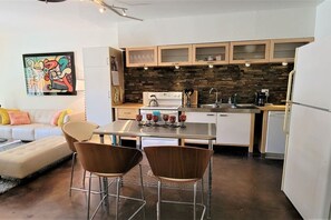 A compact kitchen with a dining area, white cabinets, a stone backsplash, and a modern coffee machine. - Ar`s Downtown Phoenix R & R A108 (Phoenix)