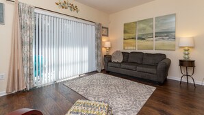 A living room with a sofa, a patterned rug, and a window with blinds. - Central Jacksonville Location! (Jacksonville)