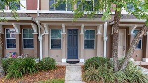 A two-story townhouse with a front door, windows, and a small porch area. - Central Jacksonville Location! (Jacksonville)