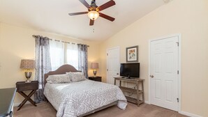 A bedroom with a bed, ceiling fan, TV, and two doors. - Central Jacksonville Location! (Jacksonville)