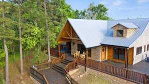 Een chalet met een stenen gevel, een metalen dak en een houten terras met een trap naar de ingang.