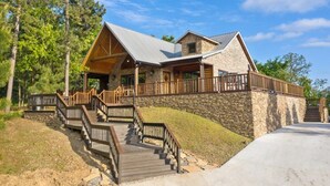 Een lodge met een stenen gevel, houten terras en metalen dak.