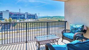 A balcony with wicker furniture and a glass table, overlooking a road and distant buildings. - Shifting Gears to Comfort -2BR/2BA @BMS, Elevator (Bristol)