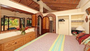 Een slaapkamer met een groot bed, een houten dressoir en een plafondventilator.