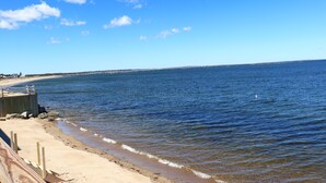 A beach with a wooden walkway leading to the water, a distant shoreline, and a clear sky. - One of kind Ocean Front Compound with private beach! (Biddeford)
