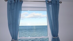 A window with a view of the sea, curtains tied back, and a metal curtain rod. - One of kind Ocean Front Compound with private beach! (Biddeford)