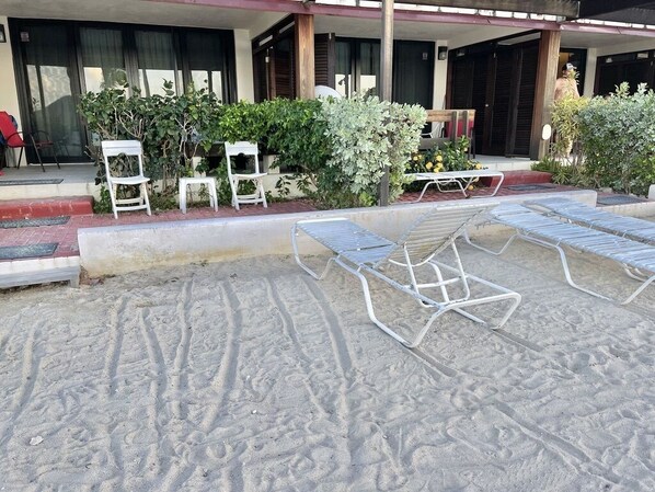 A beachside hotel with outdoor seating and a sandy area.