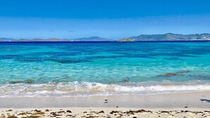 A beach with clear turquoise water, a sandy shore, and distant mountains. - Lux King Suite On Sand @ Sapphire Beach Resort II (St Thomas)