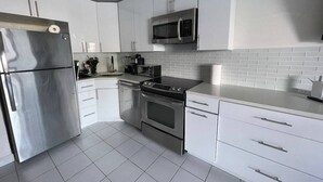 Una cocina moderna con electrodomésticos de acero inoxidable, armarios blancos y un salpicadero de azulejos.