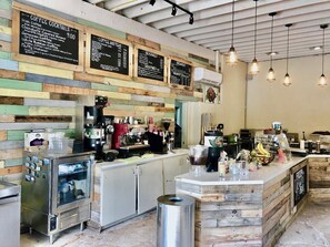 A coffee shop interior with a wooden wall, a counter with coffee machines, and a menu board.