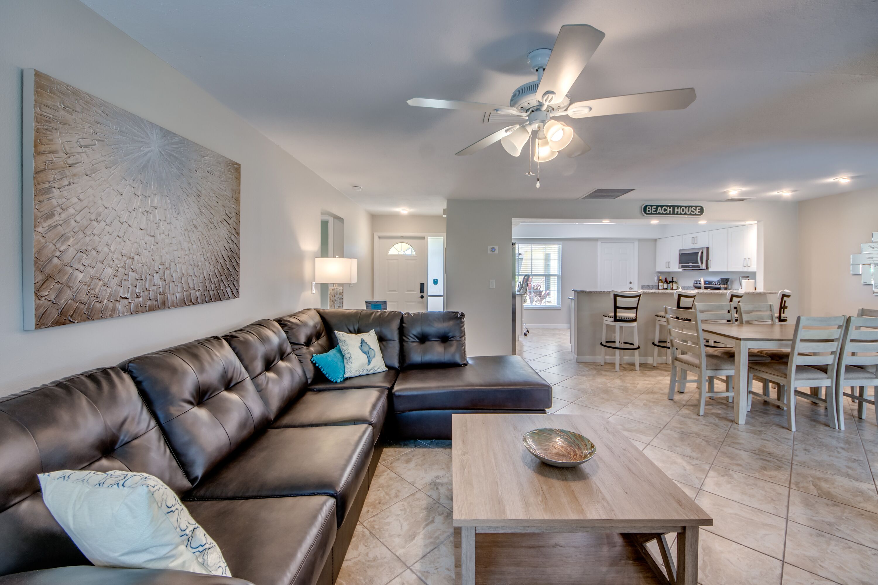 A modern living room with a leather sofa, a coffee table, and a dining area with chairs and a table.