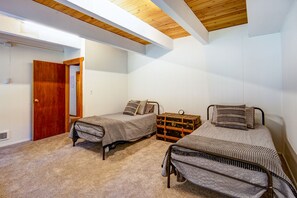 Un dormitorio con dos camas individuales, un armario de madera y un pequeño aparador.
