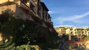 Ein mehrstöckiges Hotel mit Balkonen, Steinmauern und üppiger Bepflanzung.